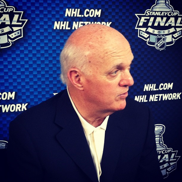 A man in suit and tie next to the nhl logo.