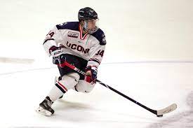 A hockey player is crouching down with his stick.