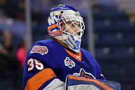 A goalie in blue and orange uniform with his face on the ice.