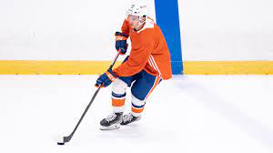 A hockey player in an orange and blue uniform.