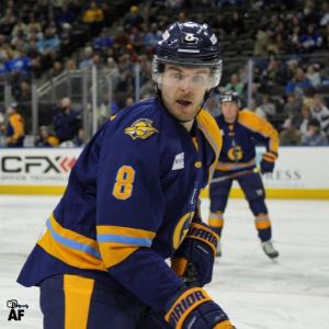 A hockey player in blue and yellow uniform on ice.