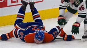 A hockey player laying on the ice after being hit by another player.